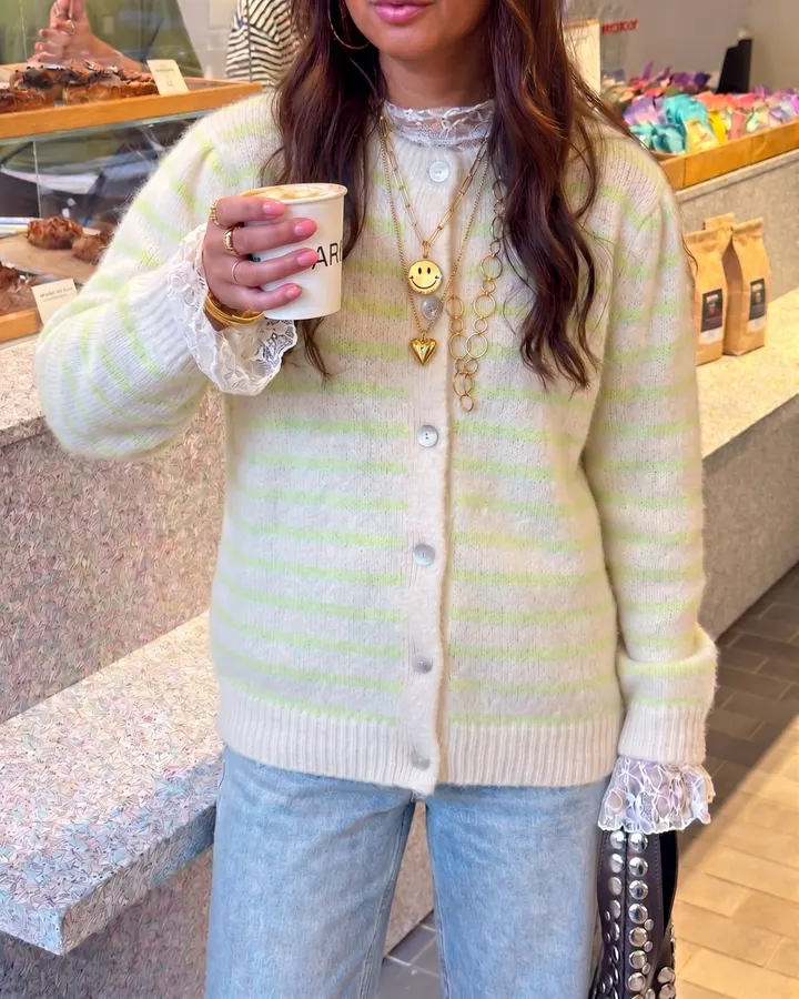 Cream cardigan with mint green stripes and lace cuffs, worn with gold necklaces